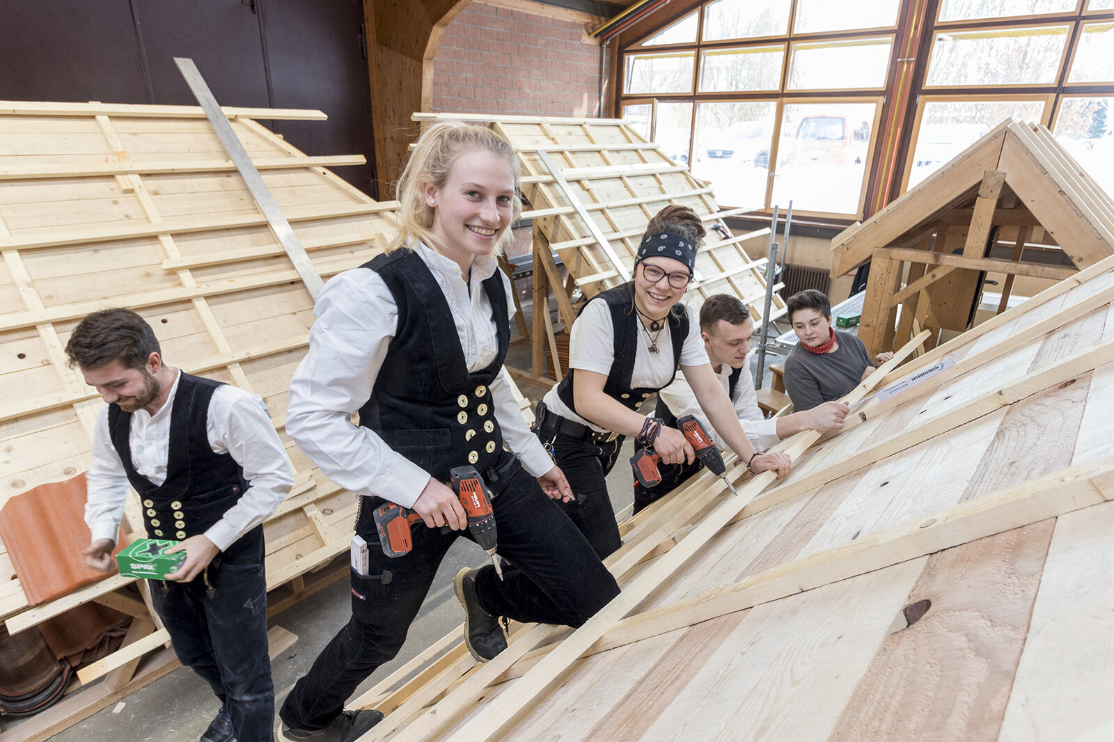 Auszubildende beim praktischen Holzhausbaukurs am Dachstuhl