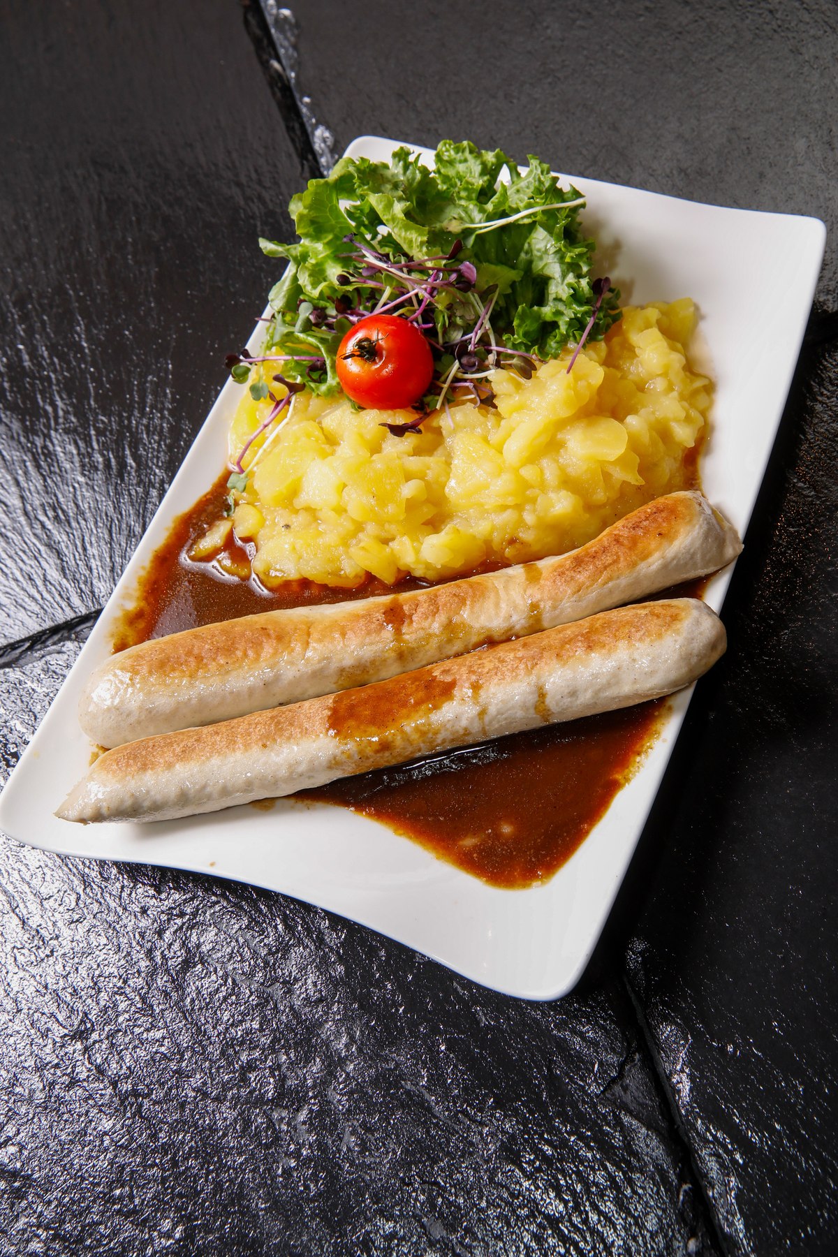 Bratwürste mit Kartoffelbrei und Bratensoße, Restaurant-Ambiente mit Kupferkesseln