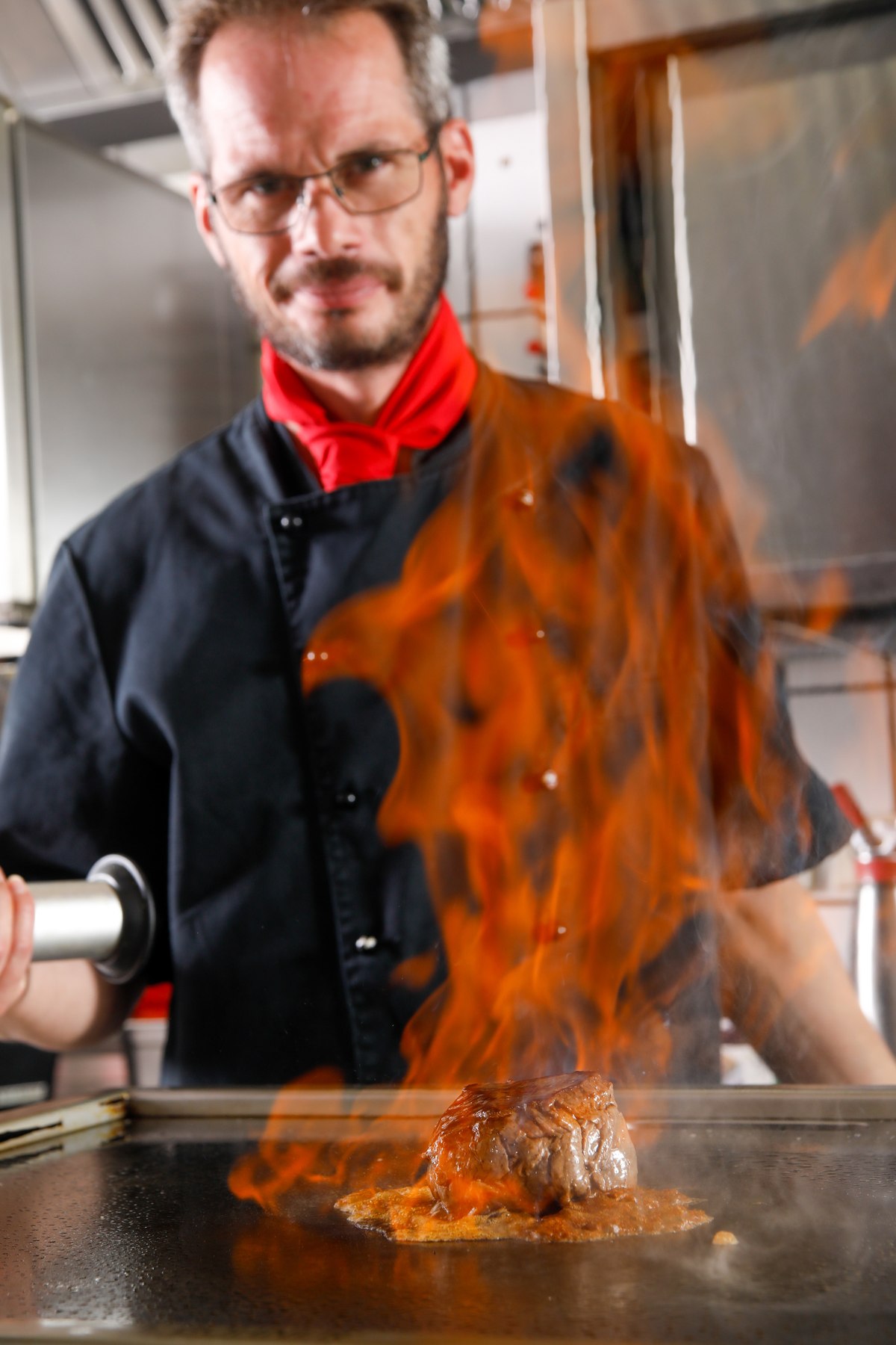 Koch beim Flambieren eines Steaks, dramatische Flammen