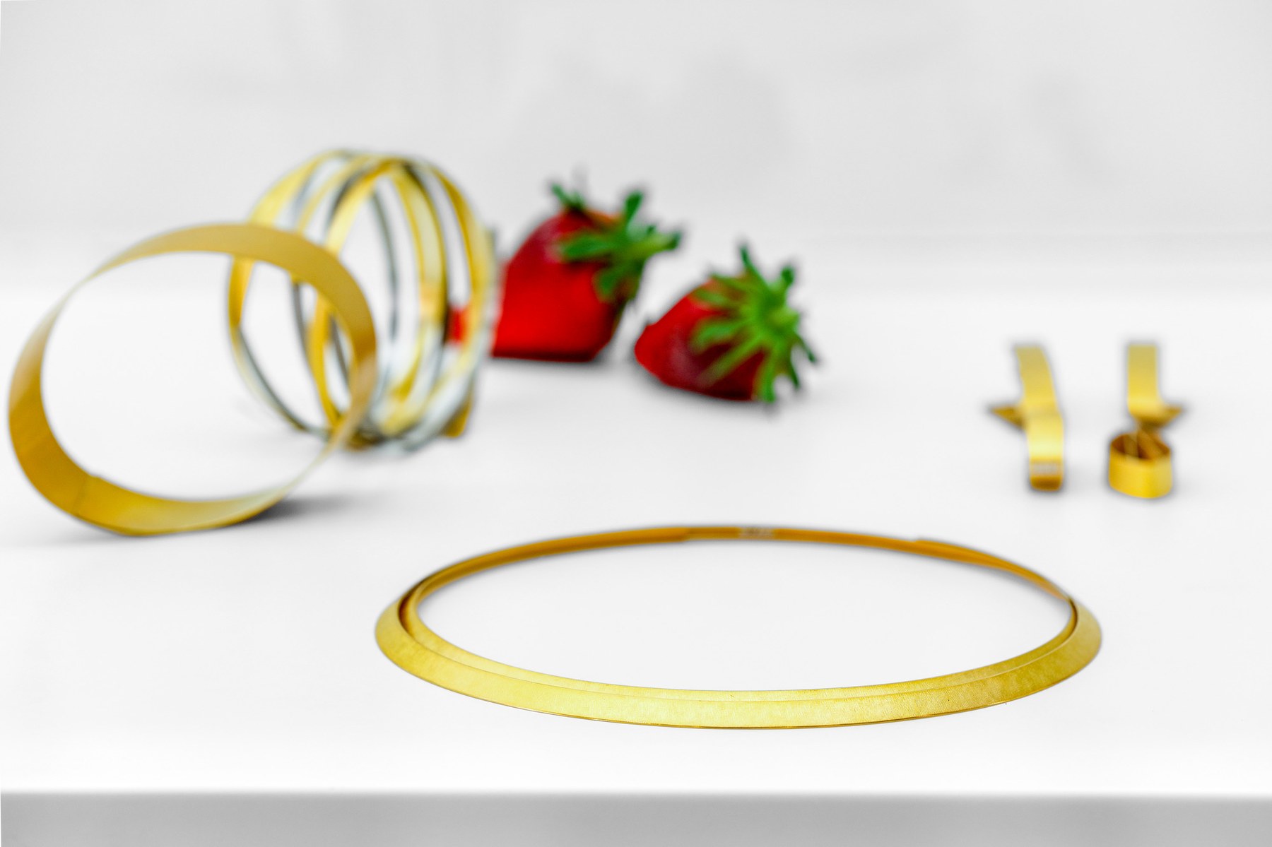 Goldene Ringe und Armreifen als Lifestyle-Komposition mit Erdbeeren