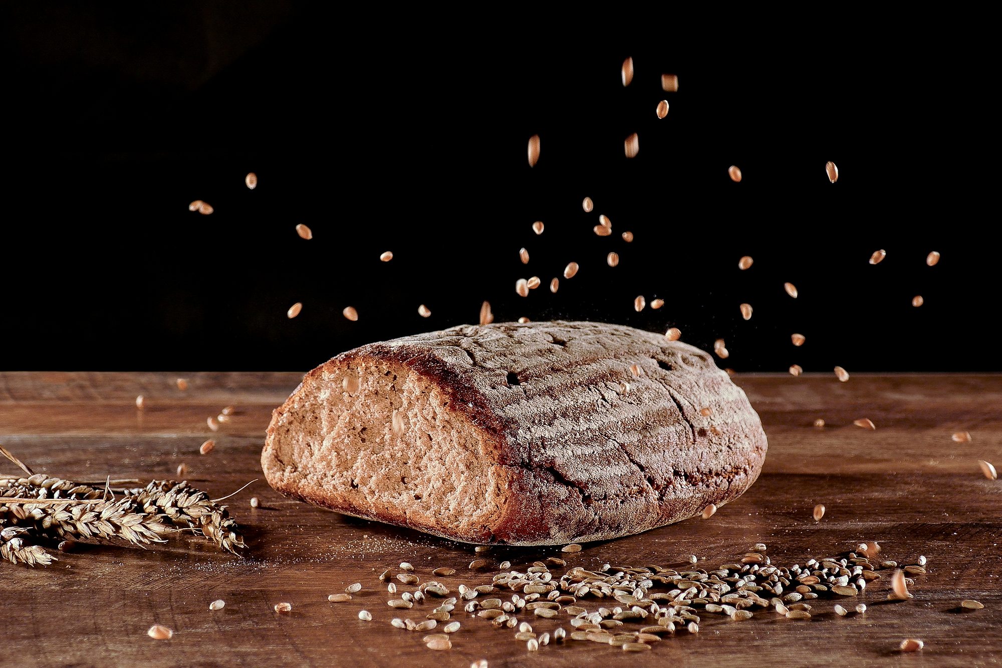 Werbefotografie – freigestelltes Brot mit fliegenden Getreidekörnern