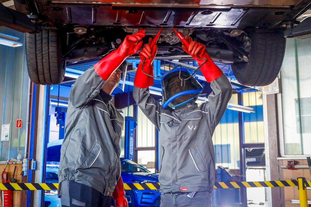 Mechaniker mit roten Handschuhen unter dem Fahrzeug