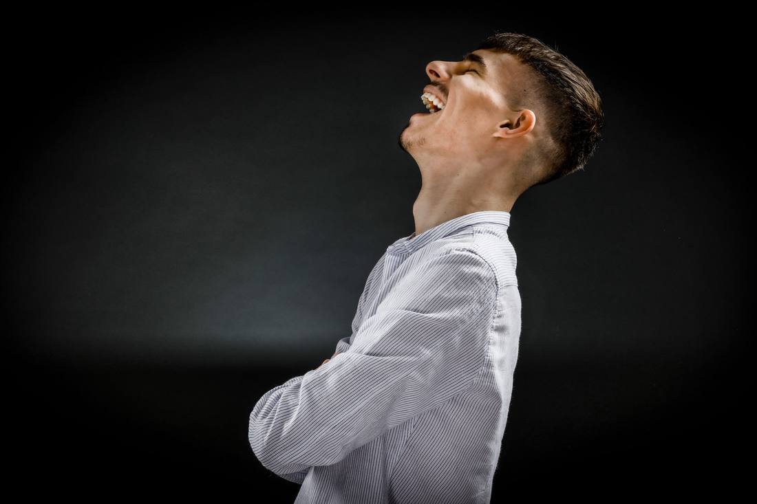 Junger Mann lacht im Profil, Studioportrait