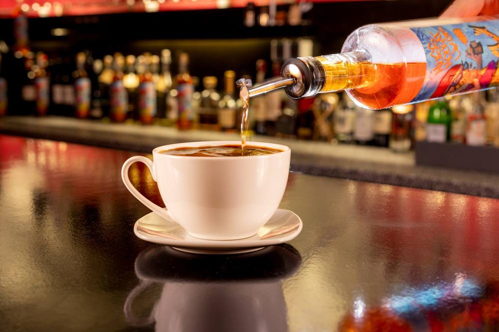 Likör wird in eine Kaffeetasse gegossen